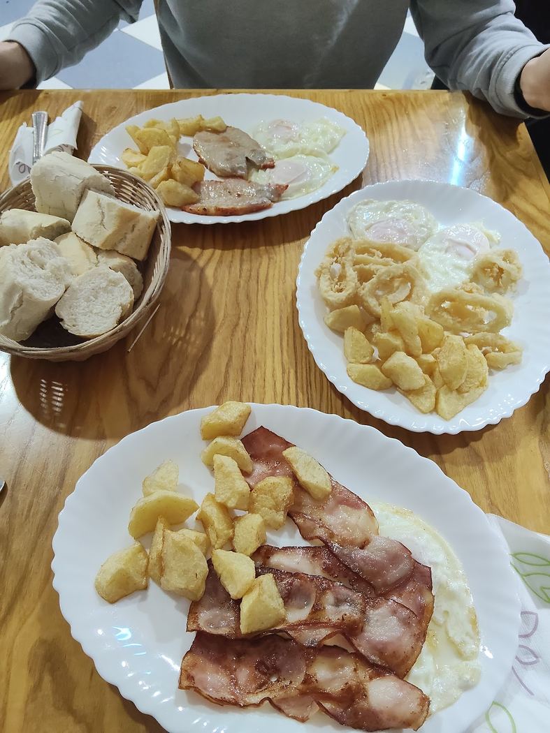 Huevos fritos con patatas caseras y acompañamiento de panceta.